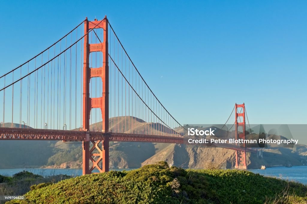 The very recognizable and iconic Golden Gate Bridge in afternoon warm light The very recognizable and iconic Golden Gate Bridge in afternoon warm light. Looking north across the bay to the hills of the Marin Headlands and Sausalito CA. Architecture Stock Photo