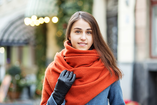 Portrait of a girl in a red hat and scarf, a walk through the Christmas city, a smile on her face, cool weather, a fascinating look.