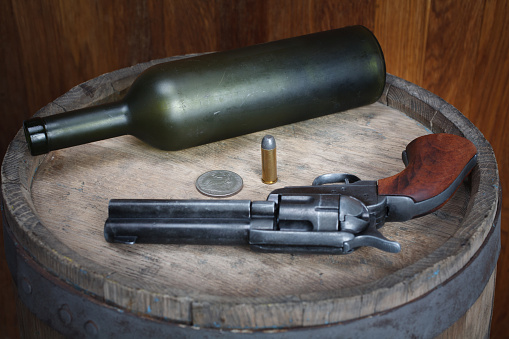 Old west revolver with cartridges on wooden barrel