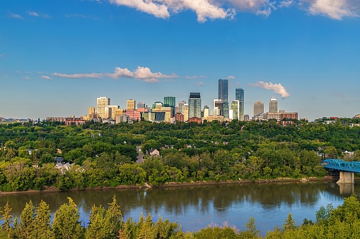 A cloudy blue sky over the Edmonton skyline and river valley in the summertime.
