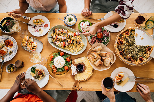 Una vista desde arriba de una mesa llena de deliciosa comida consumida por un grupo irreconocible de personas multiétnicas photo