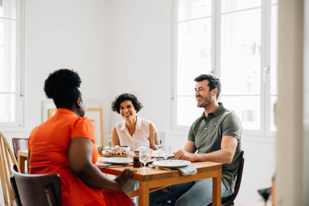 istock Three Happy Diverse Friends Sitting At The Table And Talking While Enjoying Their Lunch 1419717732