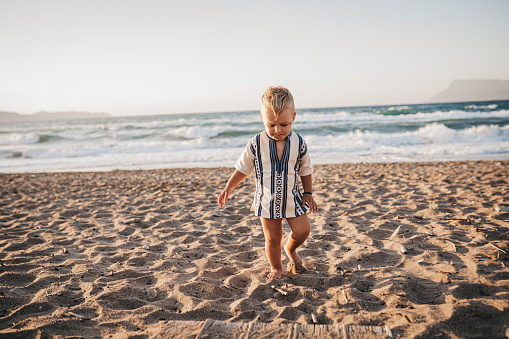 A baby boy runs on a sandy beach