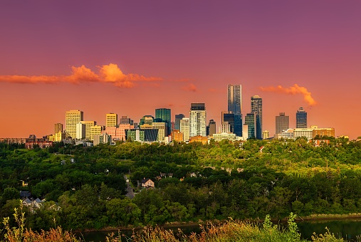 A warm sunrise glowing over the downtown Edmonton skyline in the summertime.