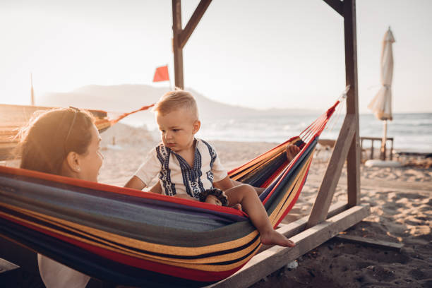 istock Cheerful boy having fun with his parent in a hammock at the beach 1419718885