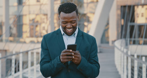 istock Happy businessman on phone browsing the internet or a social media app while standing outdoors. Male typing a email after receiving a promotion at work. Man on technology at a corporate office. 1419724721