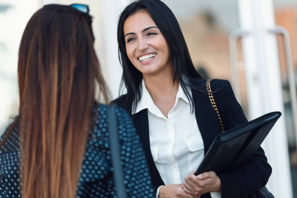 istock Two beautiful businesswomen using smart phone while drinking coffee walking around the city. 1419724829