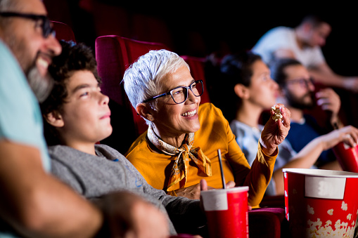 Girl watching movies at the cinema with her grandmother and grandfather.