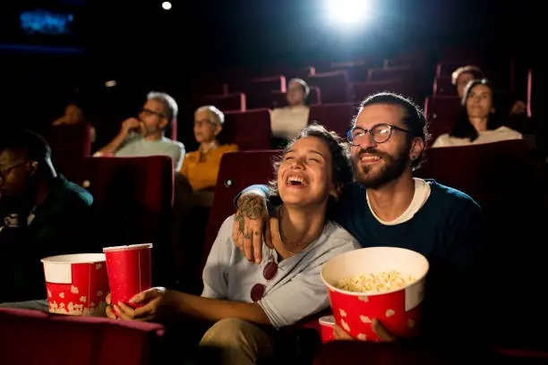 Young couple watching a movie at the cinema and enjoying.