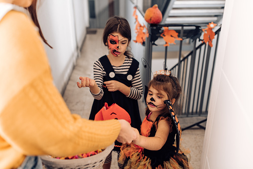 Two cute girls wearing Halloween costumes and collecting candies in the neighborhood.