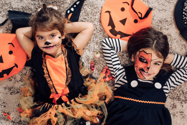 istock Two cute little sisters disguised for Halloween lying down on the floor 1419730746