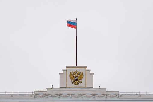 The flag and coat of arms of the Russian Federation on the administrative building. Selective focus.