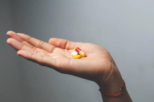 istock close up of woman's hand taking colored pills on white background 1419732220