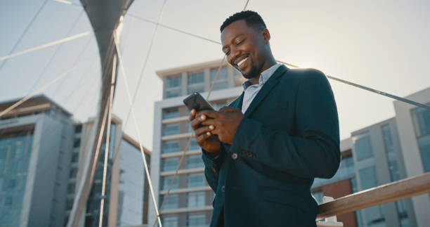 Mobile or 5g network using businessman on phone smiling, texting and talking to WhatsApp message or emails. Happy corporate man chatting or reading messages on a smartphone outdoors from work stock photo
