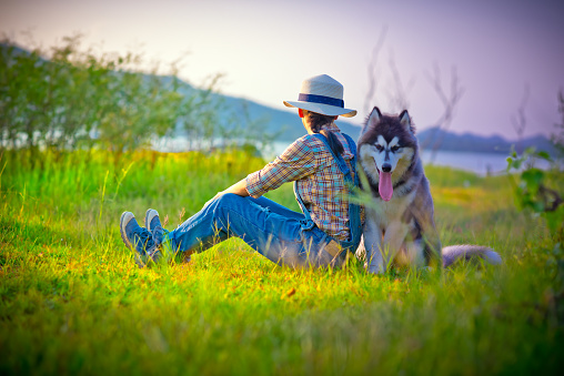 woman with dog-mate a best friend travel together in the meadow field together in holiday vacation, happy time together in light in meadow field
