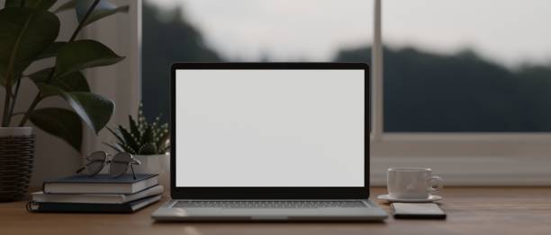 istock Modern workspace with laptop mockup, coffee cup, phone, book and glasses on wood table. 1419765713