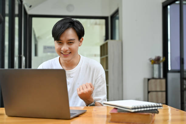 istock Excited young Asian male looking at his laptop screen, getting an unexpected email 1419765773