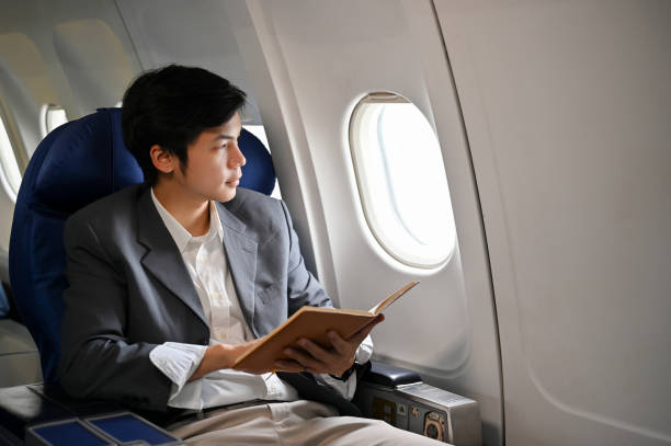 istock Successful Asian businessman holding a book while looking out the window, rduring the flight 1419766186