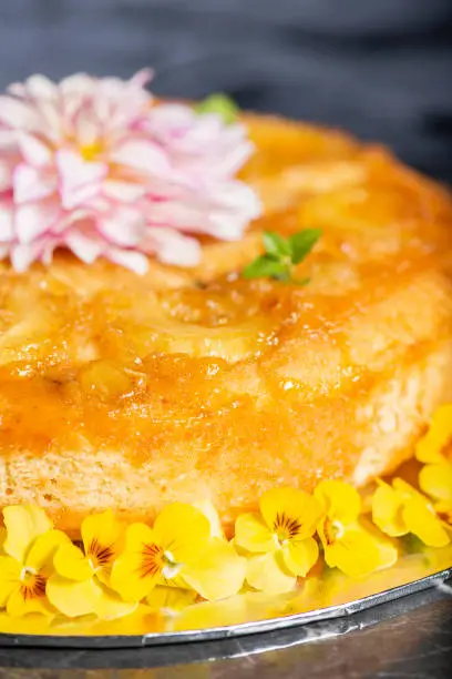 Home-made upside-down pineapple cake with mint and decorative edible flowers.