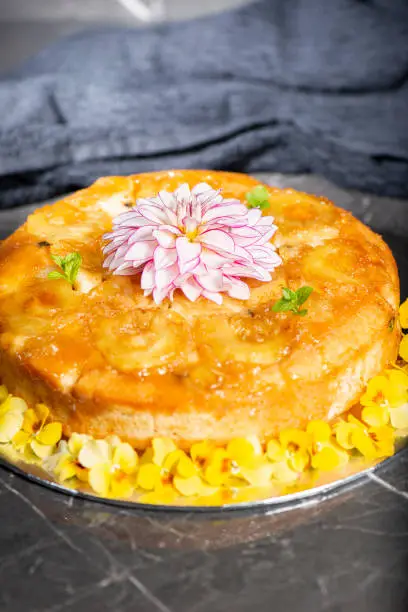 Home-made upside-down pineapple cake with mint and decorative edible flowers.