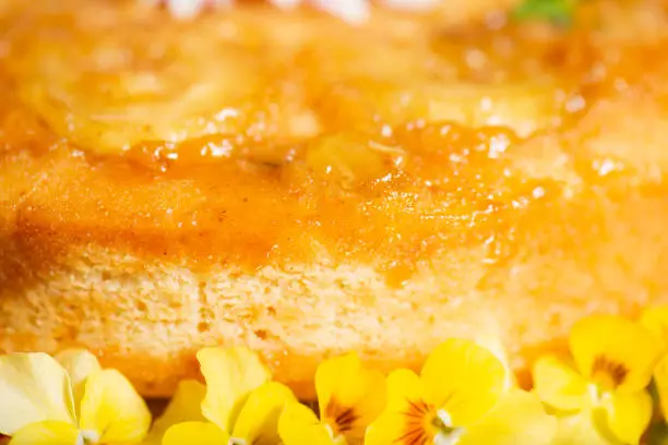 Home-made upside-down pineapple cake with mint and decorative edible flowers.