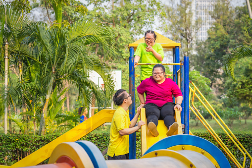 group of asian people friends with autistic or down syndrome having fun playing together at playground in park for recreation