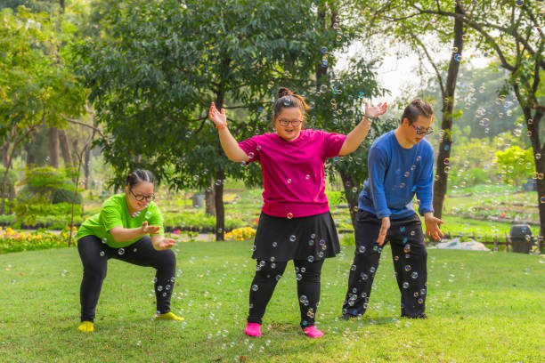 młodzi przyjaciele z autyzmem lub zespołem downa grający w bańki mydlane - asian ethnicity male park men zdjęcia i obrazy z banku zdjęć