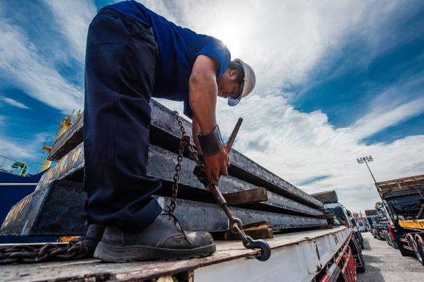 Fastening Driver foreman in takes lashing securing pressure strength fastening of the lashing chains to secured the cargo shipment fo the steel slabs carry on the truck trailer before shifting or move travel transports to cargo to destination hook equipment stock pictures, royalty-free photos & images