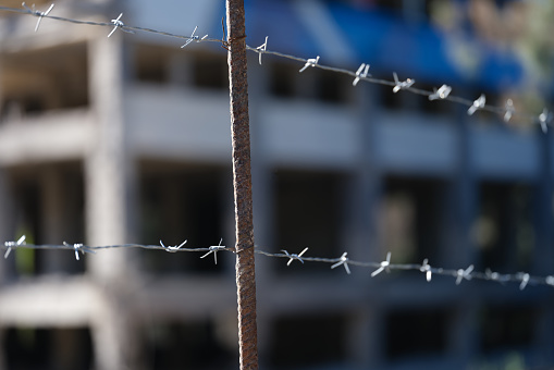 Barbed wire fence in front of prison building closeup