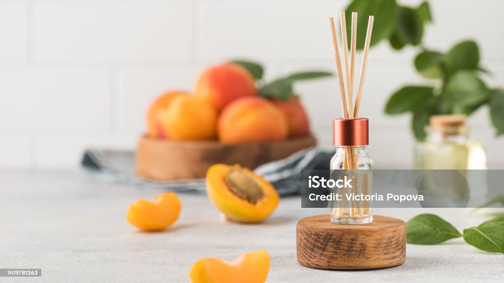Interior perfume with the scent of apricots. Jar with aroma oil and banbu sticks Interior perfume with the scent of apricots. Jar with aroma oil and banbu sticks. Design for home. Diffuser - Hair Dryer Stock Photo