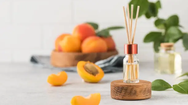 Interior perfume with the scent of apricots. Jar with aroma oil and banbu sticks. Design for home.