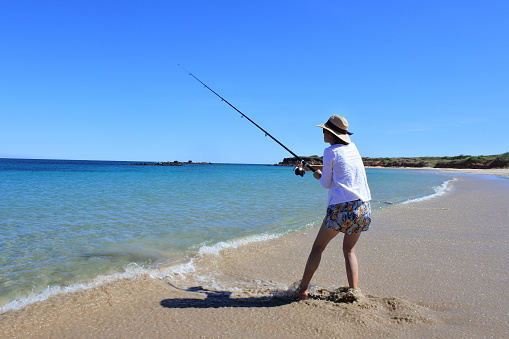 Australian woman (female age 30-40) fishing on a remote beach in the Kimberley region Western Australia
