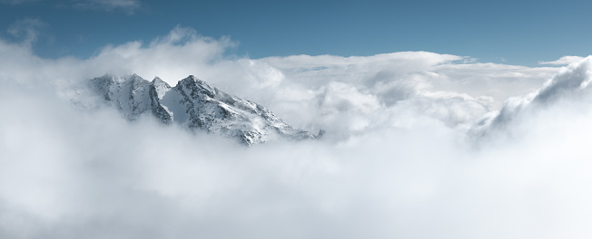 Snowcapped mountain peak looking out through the fog. Panoramic view.