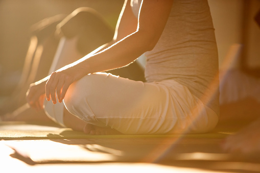 Close-up of woman meditating in lotus position, natural lens flare