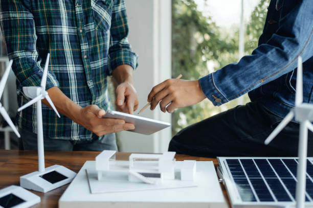 Close-up at tablet, Engineers pointing at tablet with their hands. To jointly design the use of renewable energy with wind and solar energy. Concept of using renewable energy.