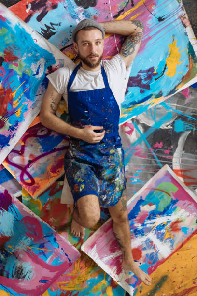 istock Confident Male Artist Laying Down On Paintings 1419791053