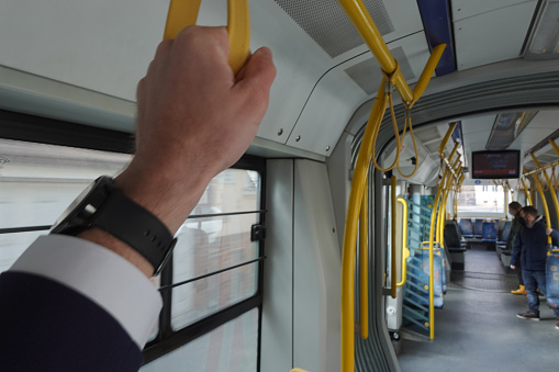 Businessman holding onto the straps with his hands on public transport
