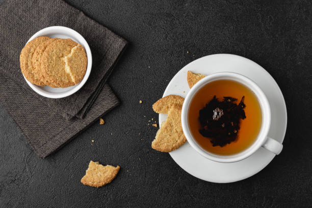 istock Cup of tea with cookies on black background. 1419799212