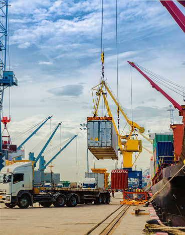 Male and female dock workers exchange work in front of port cranes