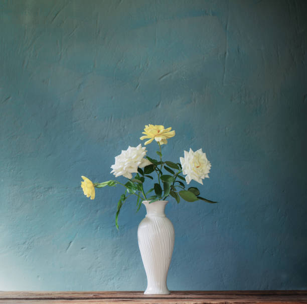 istock roses in white vase on wooden table on background dark wall 1419799838