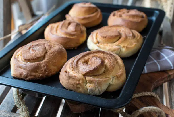 Delicious swedish cinnamon rolls, "Kanelbullar" with sugar topping. Served warm and ready to eat on a baking tray