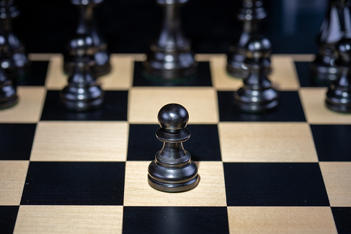 Close-up of black chess pieces on chessboard against black background.