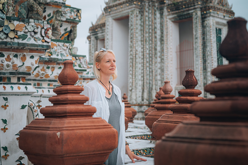 Close-up of a blond woman exploring  Wat Arun, Buddhist temple in Bangkok, Thailand
