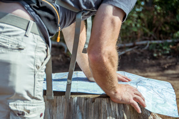 un hombre mira un mapa de senderismo en busca de orientación - scavenger hunt fotografías e imágenes de stock