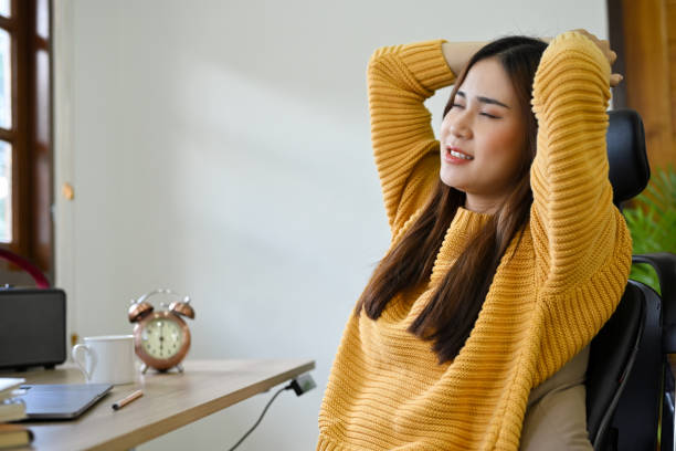 istock Relaxed Asian female leaning on her chair, hands behind her head, taking a break from work 1419809671