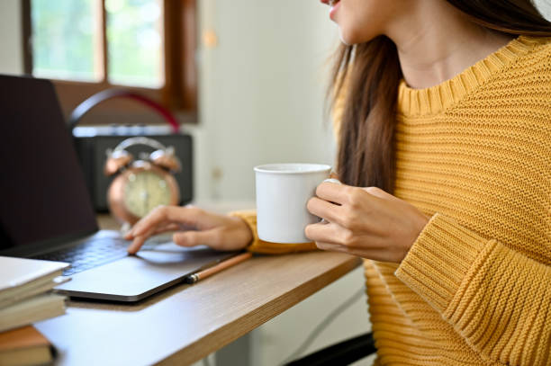 istock cropped image, A female remote working in the coffee shop, using laptop and sipping coffee. 1419810190