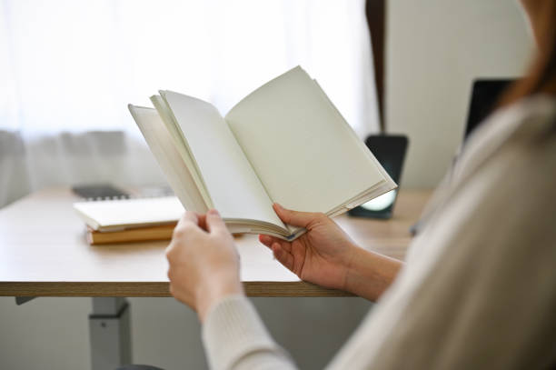 istock A pretty Asian female holding an empty notebook, reading a book or diary. cropped image. 1419810270