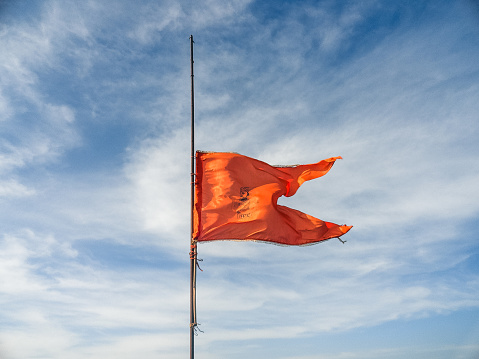 Orange Flag Of Hinduism Moving With Air On The Top of Harishchandra Fort with blue open sky in the background.