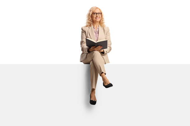istock Mature woman sitting on a blank panel and reading a book 1419819021