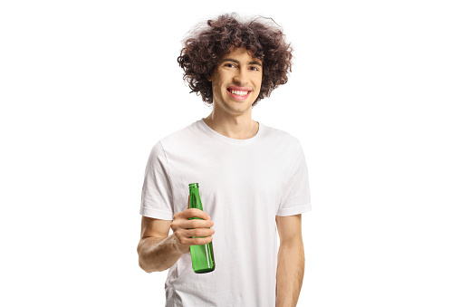 Young man with curly hair holding a bottle of beer and looking at camera isolated on white background